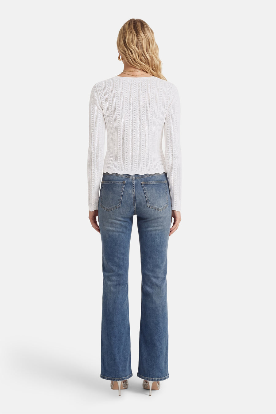 T-shirt blanc à manches longues de HAILYS, avec une texture ajourée et un ourlet festonné, à combiner avec un jean bleu et des talons.