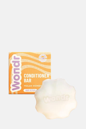 Entretien de WONDR CARE, porté dans une tresse brune sur un fond uni.