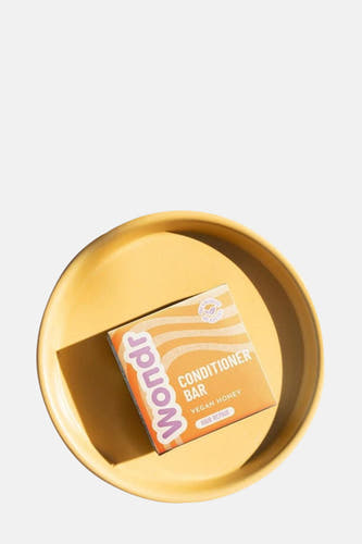 Conditionneur bar veganiste à la miel de WONDR CARE, sur un plateau jaune moutarde.