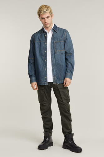 Jean cargo gris de G-Star RAW, avec des poches sur les jambes, associé à une chemise en denim et des bottes noires.