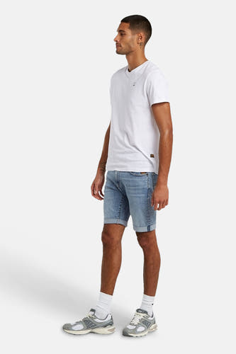 Short en jean bleu clair de G-Star RAW avec ourlets retroussés, porté par un homme avec un t-shirt blanc et des baskets, en vue de côté.