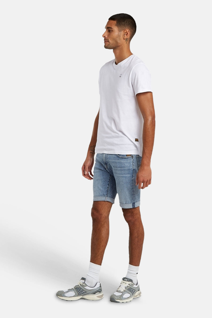 Short en jean bleu clair de G-Star RAW avec ourlets retroussés, porté par un homme avec un t-shirt blanc et des baskets, en vue de côté.