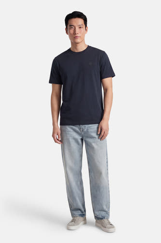 Blauw T-shirt met korte mouwen van G-Star RAW, gecombineerd met een lichtblauwe jeans en grijze sneakers.