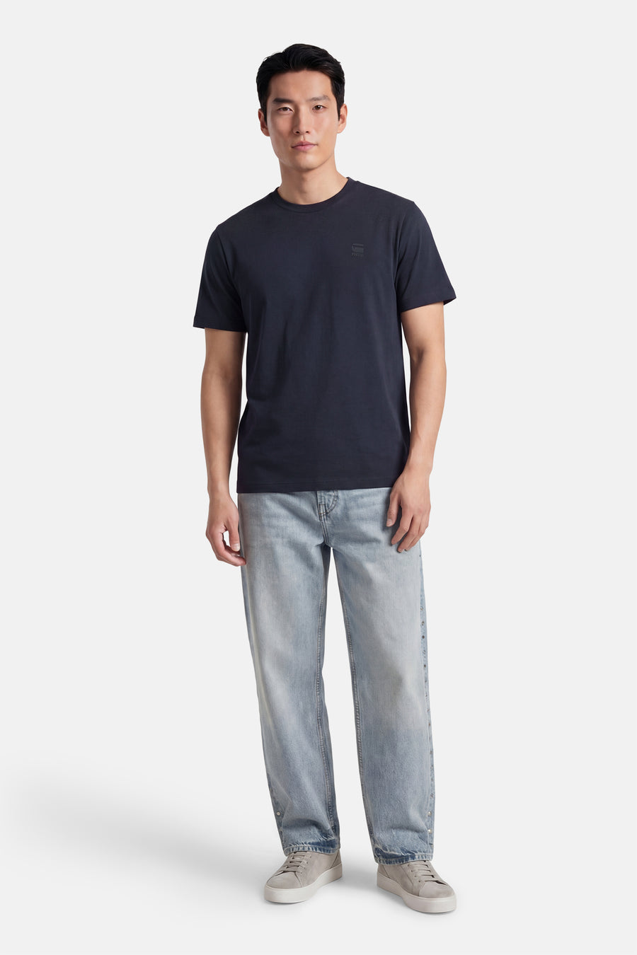 Blauw T-shirt met korte mouwen van G-Star RAW, gecombineerd met een lichtblauwe jeans en grijze sneakers.