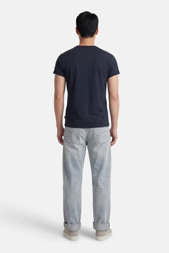 Blauw T-shirt met korte mouwen van G-Star RAW, gezien van achteren, gecombineerd met lichtblauwe jeans en sneakers.
