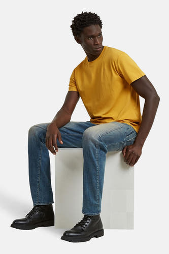T-shirt à manches courtes jaune de G-Star RAW, porté avec un jean bleu et des bottes en cuir noir.