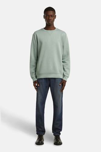 Pull-over vert vert avec col rond de G-Star RAW, associé à des jeans foncés et des chaussures noires.