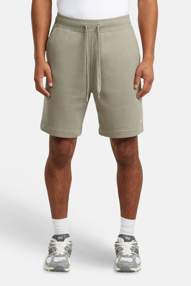Short de survêtement gris de G-Star RAW, vue arrière avec poche arrière plaquée et étiquette de marque, porté avec des chaussettes blanches et des baskets.