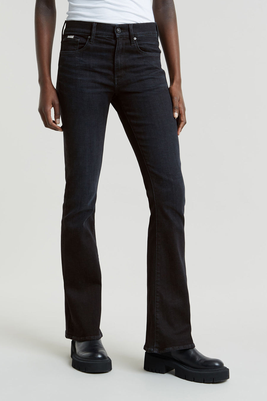Jean flare noir de G-Star RAW, avec un lavage subtil et associé à des chaussures en cuir noires à semelles épaisses.
