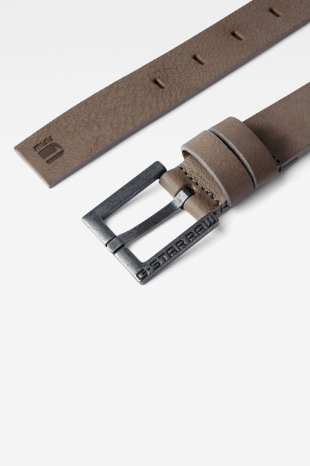 Ceinture grise de G-Star RAW, avec une boucle argentée à logo de marque sur un fond blanc.