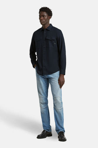 Chemise bleue à manches longues de G-Star RAW, avec deux poches poitrine, portée avec un jean et des chaussures noires.