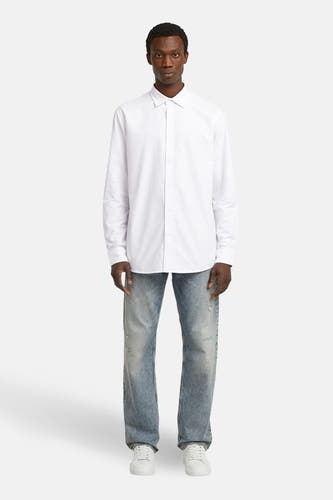 Blouse blanche à manches longues de G-Star RAW, portée avec des jeans et des baskets blanches.