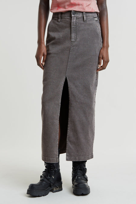 Jupe longue en denim gris foncé de G-Star RAW, avec une fente haute à l'avant, portée avec un haut rose et des bottes noires.