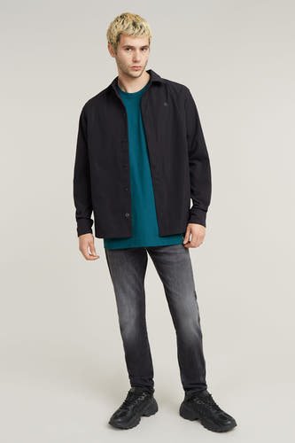 Jean slim de denim gris foncé de G-Star RAW, associé à un t-shirt vert et des baskets noires.