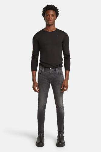 Jean skinny de G-Star RAW, avec un lavage gris foncé et porté avec une chemise noire et des bottes.