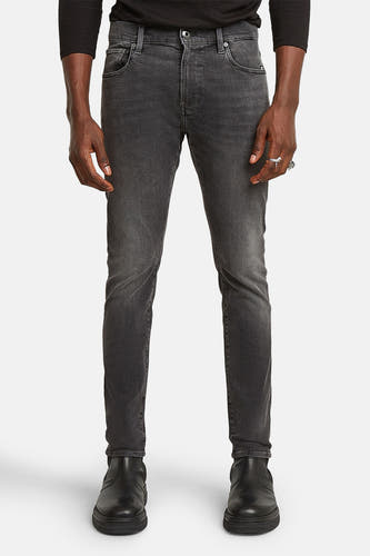 Jean skinny gris G-Star RAW, avec un lavage subtil et porté avec des bottes noires.