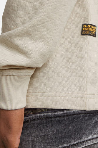 Gilet écru de G-Star RAW, avec des manches côtelées et une texture tissée, associé à un jean gris.