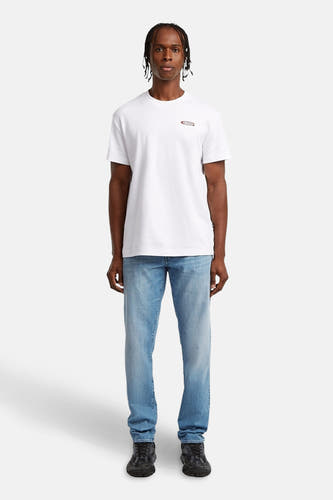 Jean tapered en denim bleu clair de G-Star RAW, porté avec un t-shirt blanc et des baskets noires.