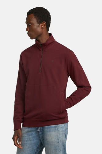 Gilet de Bordeaux de G-Star RAW, avec une fermeture éclair courte et une poche sur l'avant, porté avec un pantalon de cuir bleu.