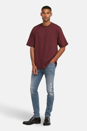 T-shirt Bordeaux à manches courtes de G-Star RAW, porté avec des jeans bleus déchirés et des chaussures noires en filet.