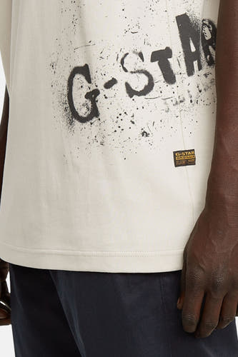 T-shirt écru à manches courtes de G-Star RAW, avec imprimé logo noir et étiquette de marque sur le côté.