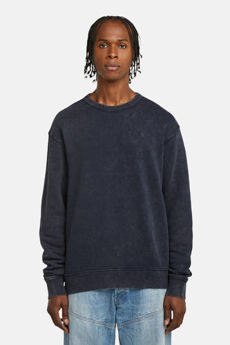 Pull-over bleu de G-Star RAW, avec des manches longues et porté avec un jean.