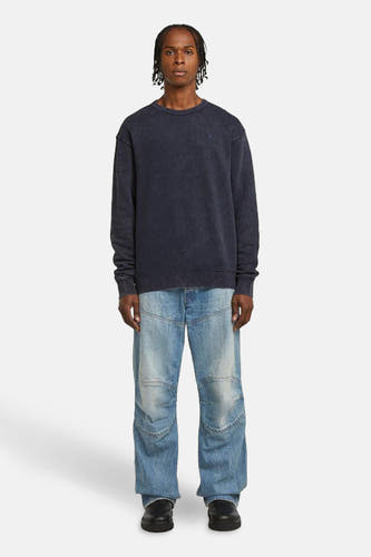 Pull-over bleu avec col rond de G-Star RAW, porté avec un pantalon de jeans large et clair bleu et des chaussures noires.