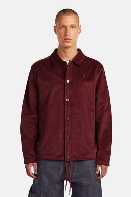 Een man die een bordeauxrode corduroy jas draagt.