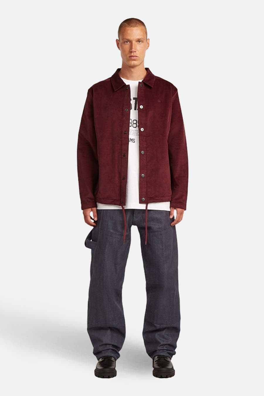 Veste rouge de G-Star RAW, à fermeture à boutons et à coupe décontractée, associée à un T-shirt blanc et à des pantalons larges et sombres.