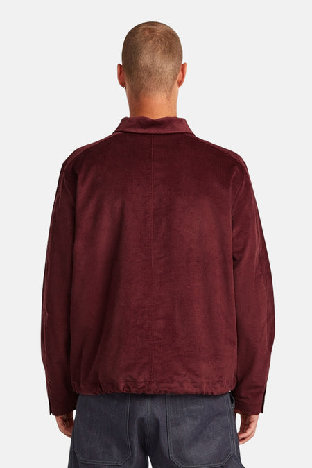 Achterkant van een man in een bordeauxrood corduroy jasje.