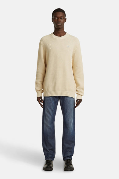 T-shirt écru avec col rond de G-Star RAW, porté avec des jeans bleus et des chaussures noires.