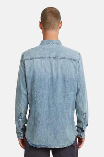 Achterkant van een lichtblauw denim overhemd.