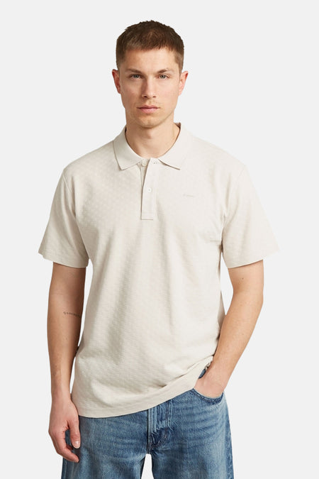 Polo écru de G-Star RAW, avec motif géométrique subtil, portée avec un jean ample et des chaussures noires.