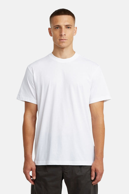 T-shirt blanc à manches courtes de G-Star RAW, avec imprimé au dos, porté avec un pantalon foncé.