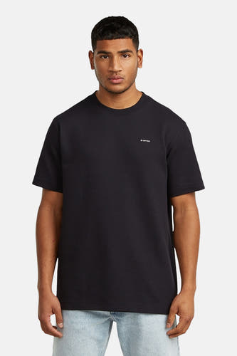 T-shirt noir à manches courtes de G-Star RAW, porté avec un jean bleu clair et des chaussures en cuir noires.