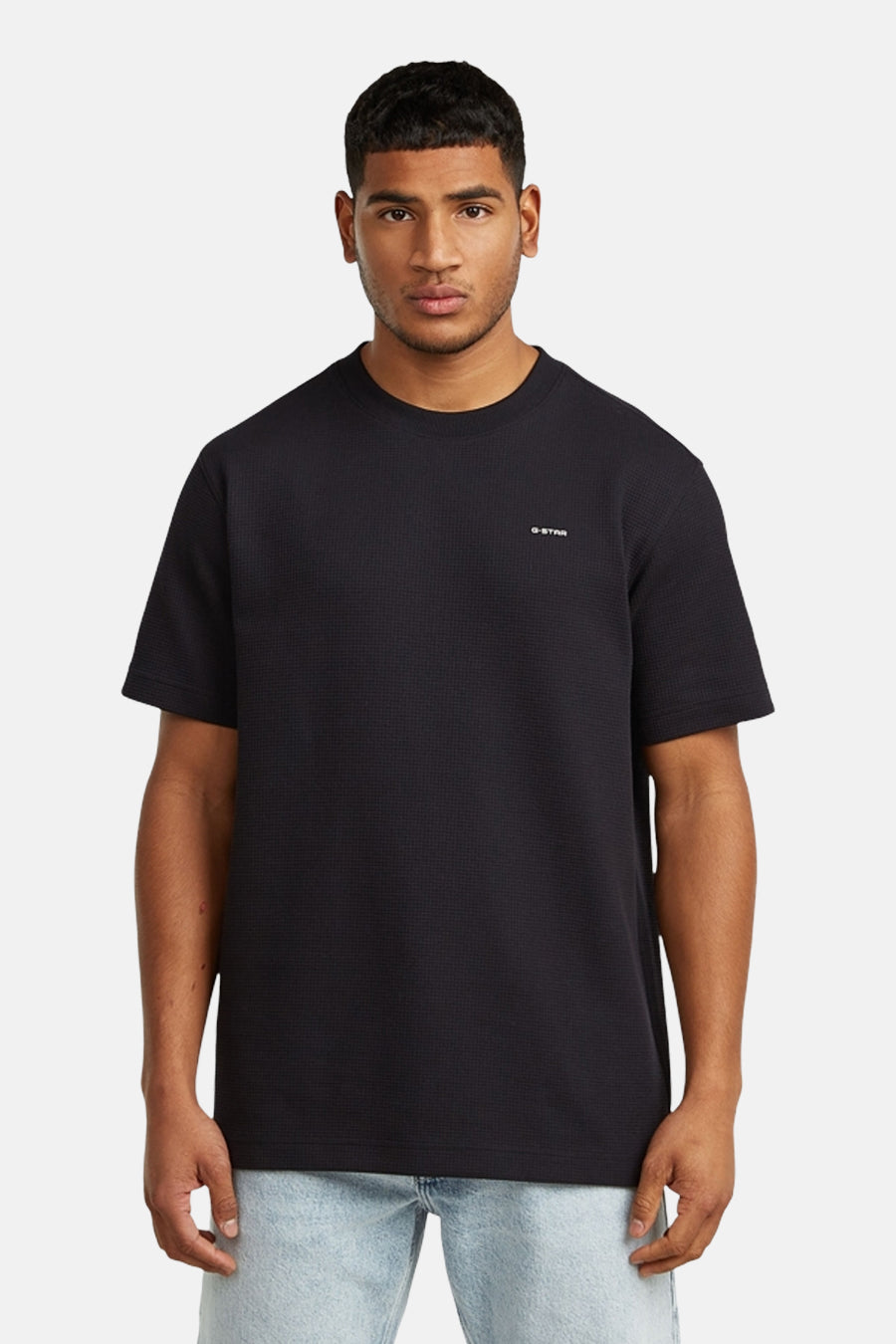T-shirt noir à manches courtes de G-Star RAW, porté avec un jean bleu clair et des chaussures en cuir noires.