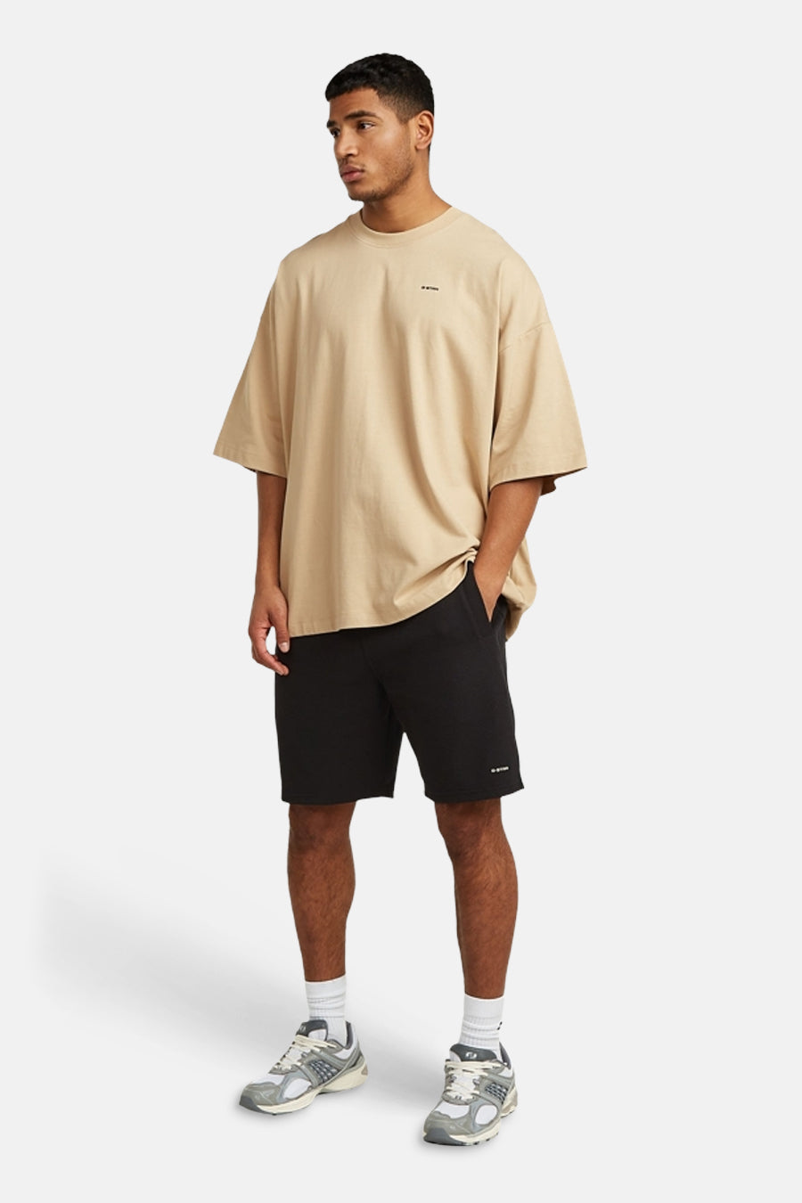 Short noir de G-Star RAW, porté avec un t-shirt beige, des chaussettes blanches et des baskets.