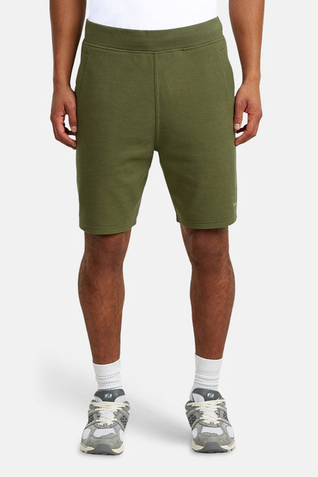 Short vert de G-Star RAW, avec une subtile texture gaufrée, porté avec des chaussettes blanches et des baskets, vu de dos.