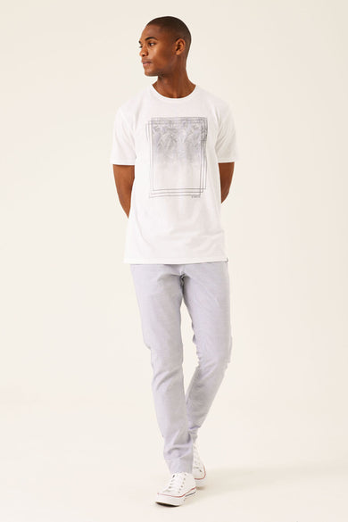 T-shirt blanc à manches courtes de GARCIA, avec une impression graphique et associé à un pantalon gris clair et des baskets blanches.