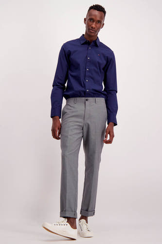 Chemise bleue à manches longues de TOMMY JEANS, simple et portée avec un pantalon gris et des baskets blanches.