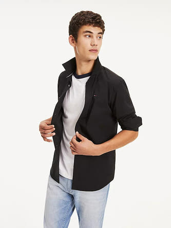 Chemise noire à manches longues de TOMMY JEANS, dos nu, portée avec un jean.