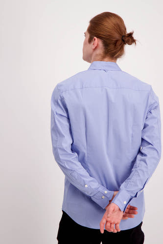 Chemise bleue à manches longues de TOMMY JEANS, dos, avec les mains derrière le dos.