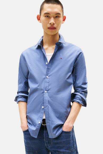 Chemise bleue à manches longues de TOMMY JEANS, vue de derrière, avec des jeans foncés et des chaussures blanches.