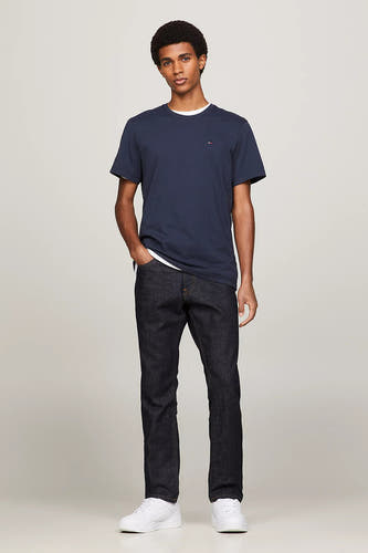 T-shirt bleu de TOMMY JEANS, porté avec des jeans foncés et des baskets blanches.