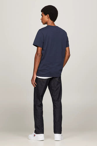 T-shirt bleu de TOMMY JEANS, vue arrière, associé à des jeans foncés et des baskets blanches.