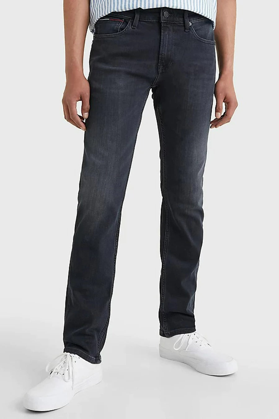 Jean slim fit couleur gris anthracite de TOMMY JEANS, associé à une chemise rayée bleue et des baskets blanches, vu de dos.