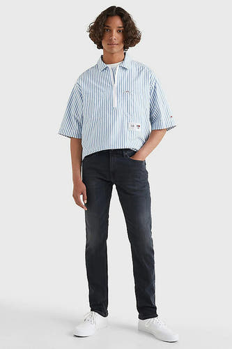 Donkergrijze slim fit jeans van TOMMY JEANS, met een licht verwassen textuur, gecombineerd met een gestreept overhemd en witte sneakers.