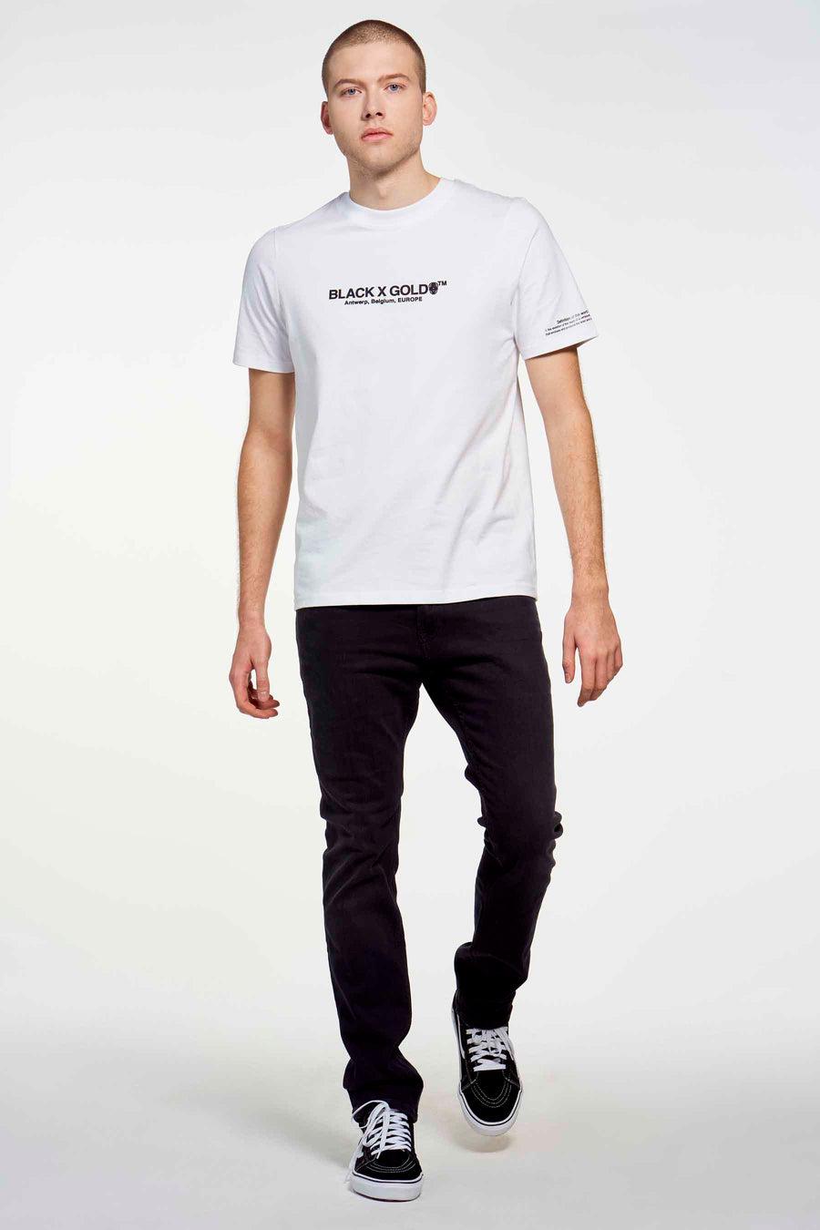 Jean slim gris foncé de TOMMY JEANS, associé à un T-shirt blanc et des baskets basses noires.