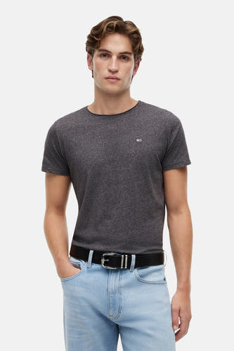 T-shirt noir de TOMMY JEANS, à manches courtes, porté avec une ceinture noire et un jean clair.