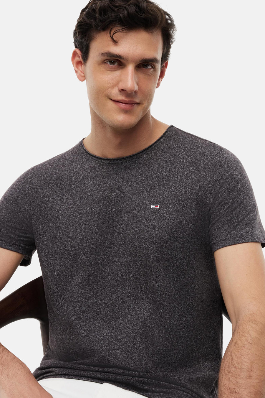 T-shirt noir chiné à col rond de TOMMY JEANS, avec petit logo sur la poitrine, porté par un homme dans une photo lifestyle